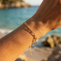 Thumbnail for Paperclip Chain Bracelet by Brother & Sisters on a wrist with clean links near the beach, showcasing its stylish elegance.