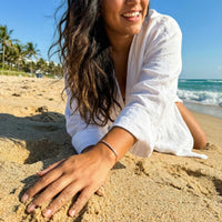 Thumbnail for Woman lying on the sand in a white shirt wearing the rose gold Crystal Bar Bracelet