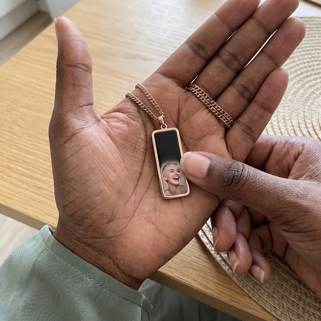 Thumb warming the rose gold bar pendant: the hidden photo appears under the thumb while the rest stays black | SKU: TPH-BARN-ROSEGOLD