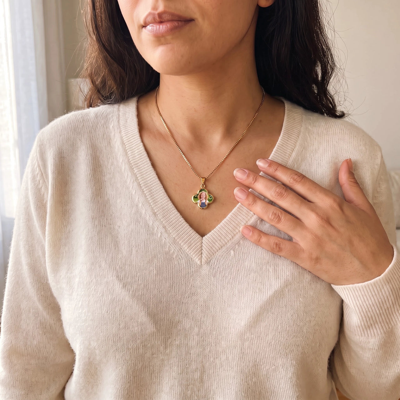 Woman in a cream V-neck sweater, hand on her chest, wearing the gold secret clover photo necklace | SKU: TPH-CLVN-GOLD