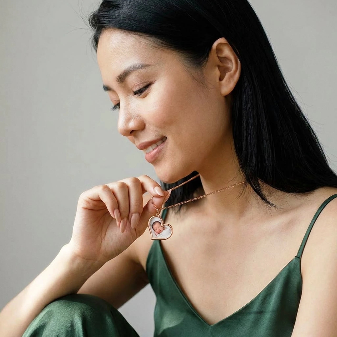 Woman looking tenderly at her baby's photo in the rose gold secret heart necklace | SKU: TPH-HRTN-ROSEGOLD