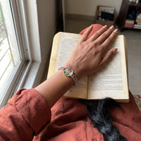 Thumbnail for Her hand resting on an open book, the silver round photo bracelet with her grandmother's photo | SKU: TPH-RNDB-SILVER